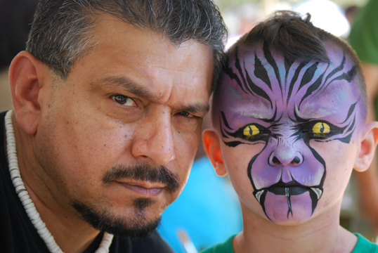 Mark Reid posing with a young boy he face painted with a purple monster theme